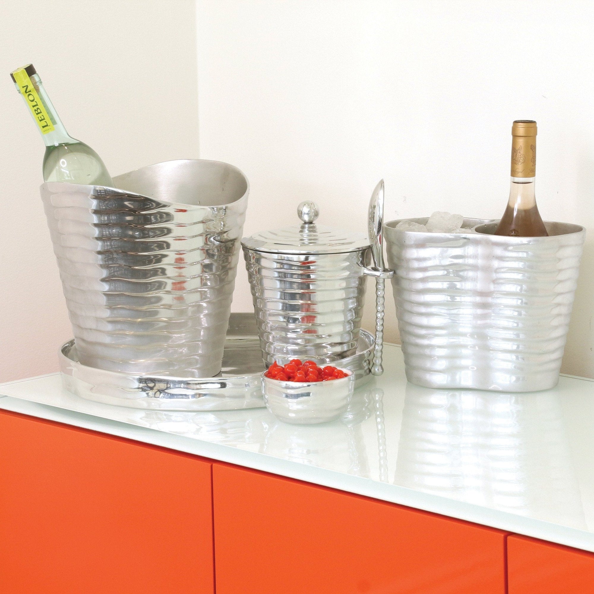 Metallic ice buckets with bottles on a white countertop with orange cabinets