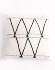 An 18x18 inch Atlas throw pillow with a white background and black geometric patterns, hand-woven and embroidered with tassels