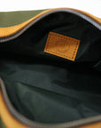 An unzipped green toiletry bag with leather accents and a metal zipper.