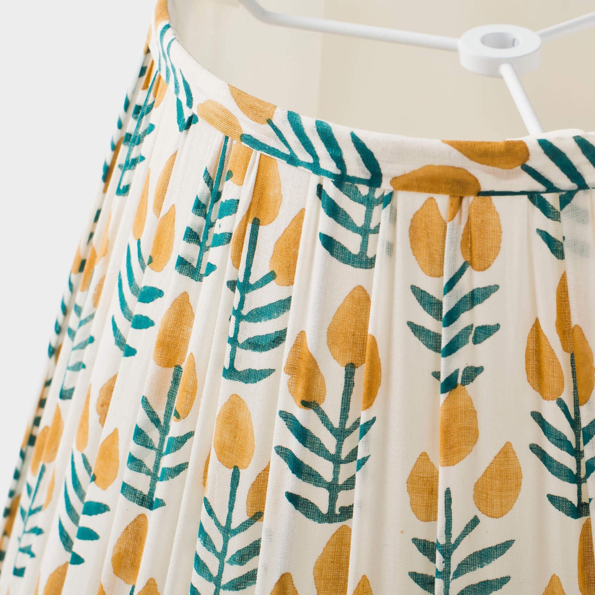 Up-close of a lamp shade with yellow and green leaf pattern.