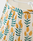 Up-close of a lamp shade with yellow and green leaf pattern.