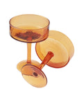 A set of four handblown hammered amber-colored cocktail glasses, including a cup and a saucer, made from recycled glass