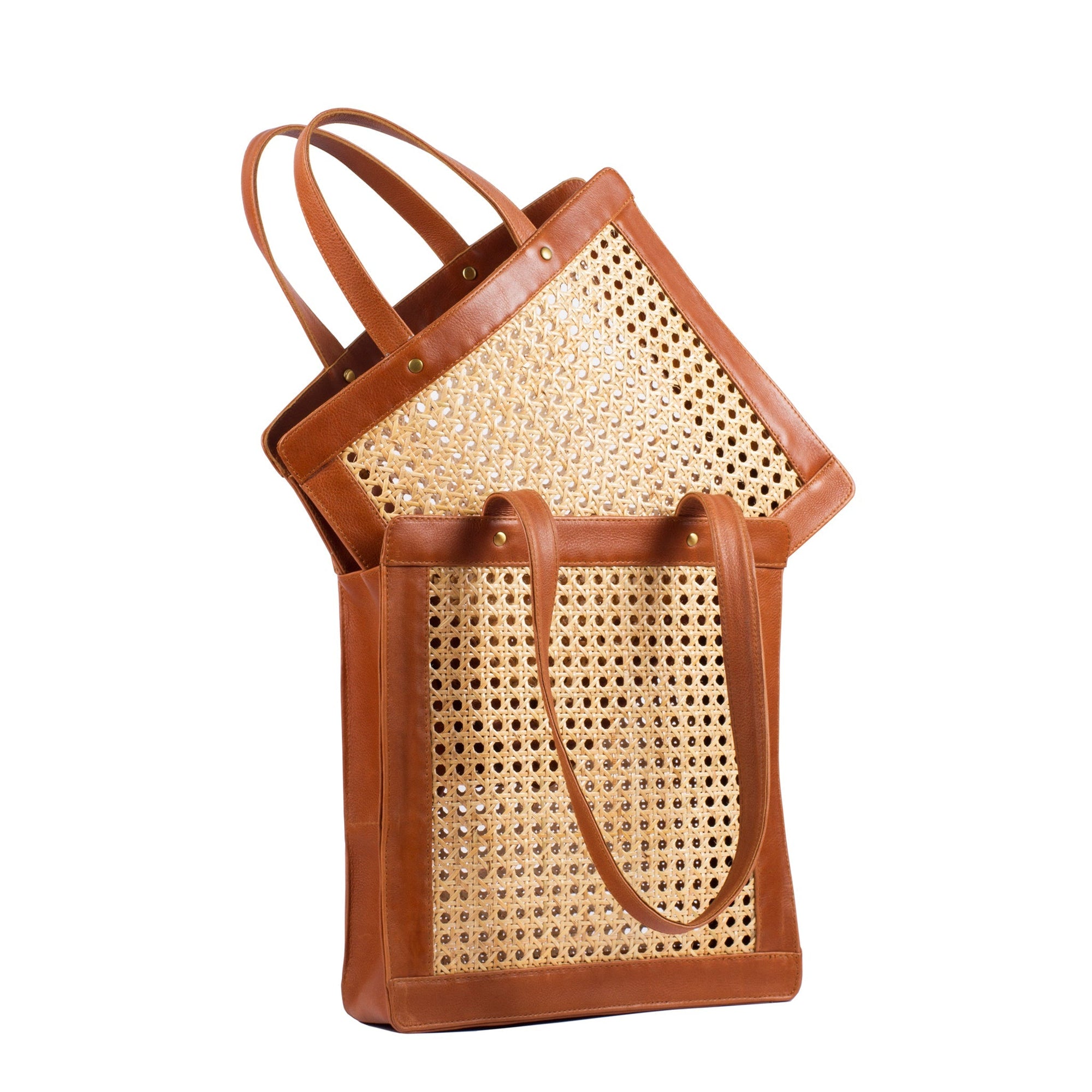 Two brown leather tote bags with rattan cane webbing and leather handles. One is one top of the other one.