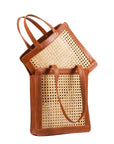 Two brown leather tote bags with rattan cane webbing and leather handles. One is one top of the other one.