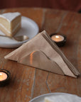 A cloud design napkin holder on holding napkins next to candles and a desert