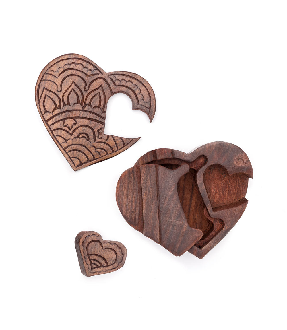 The puzzle pieces of a hand-carved wooden puzzle box in the shape of a heart with intricate floral patterns.