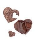 The puzzle pieces of a hand-carved wooden puzzle box in the shape of a heart with intricate floral patterns.