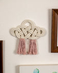 Decorative cotton wall piece with braided design and tassels on a wall next to framed pictures