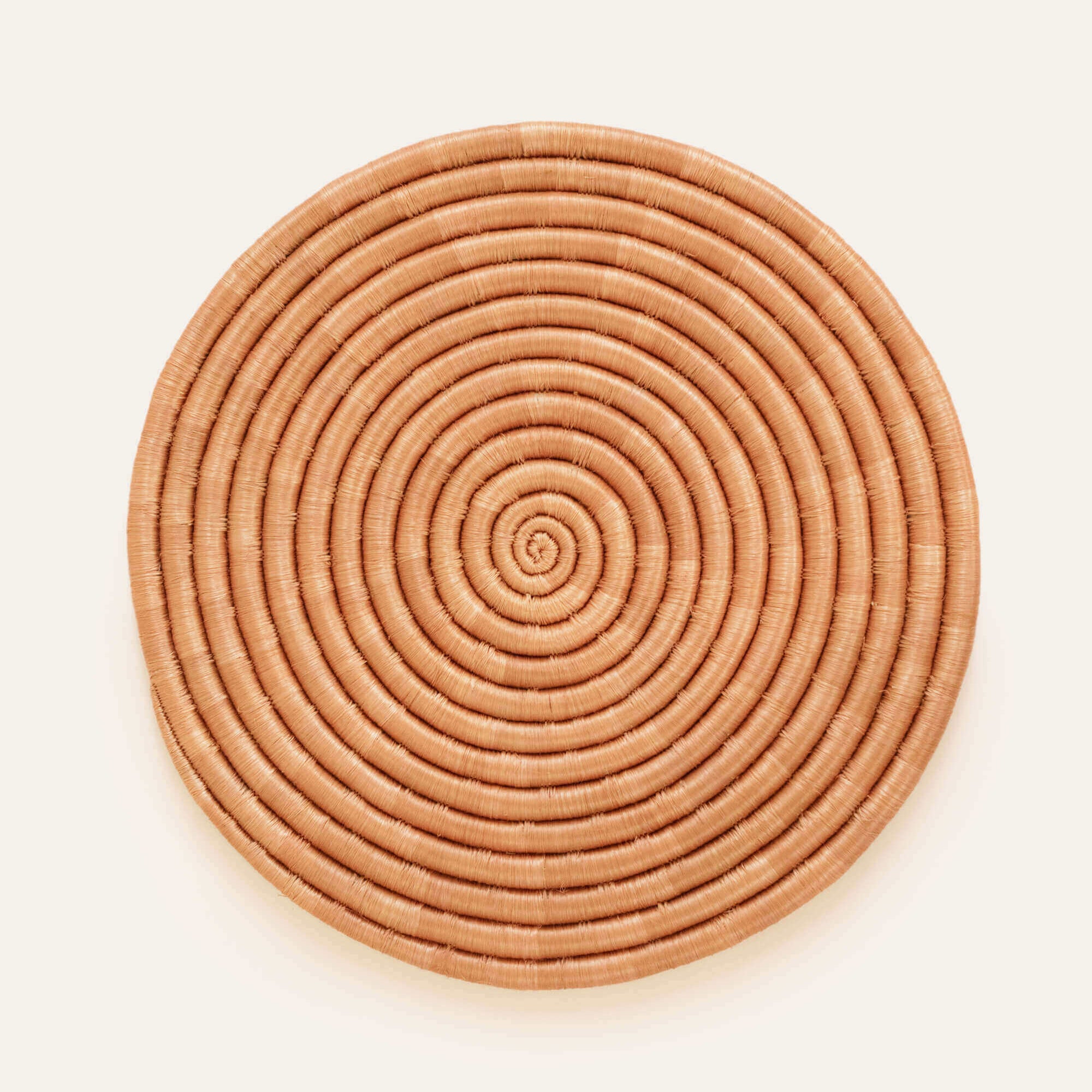 A round, beige sisal placemat with a geometric pattern, crafted from natural fibers
