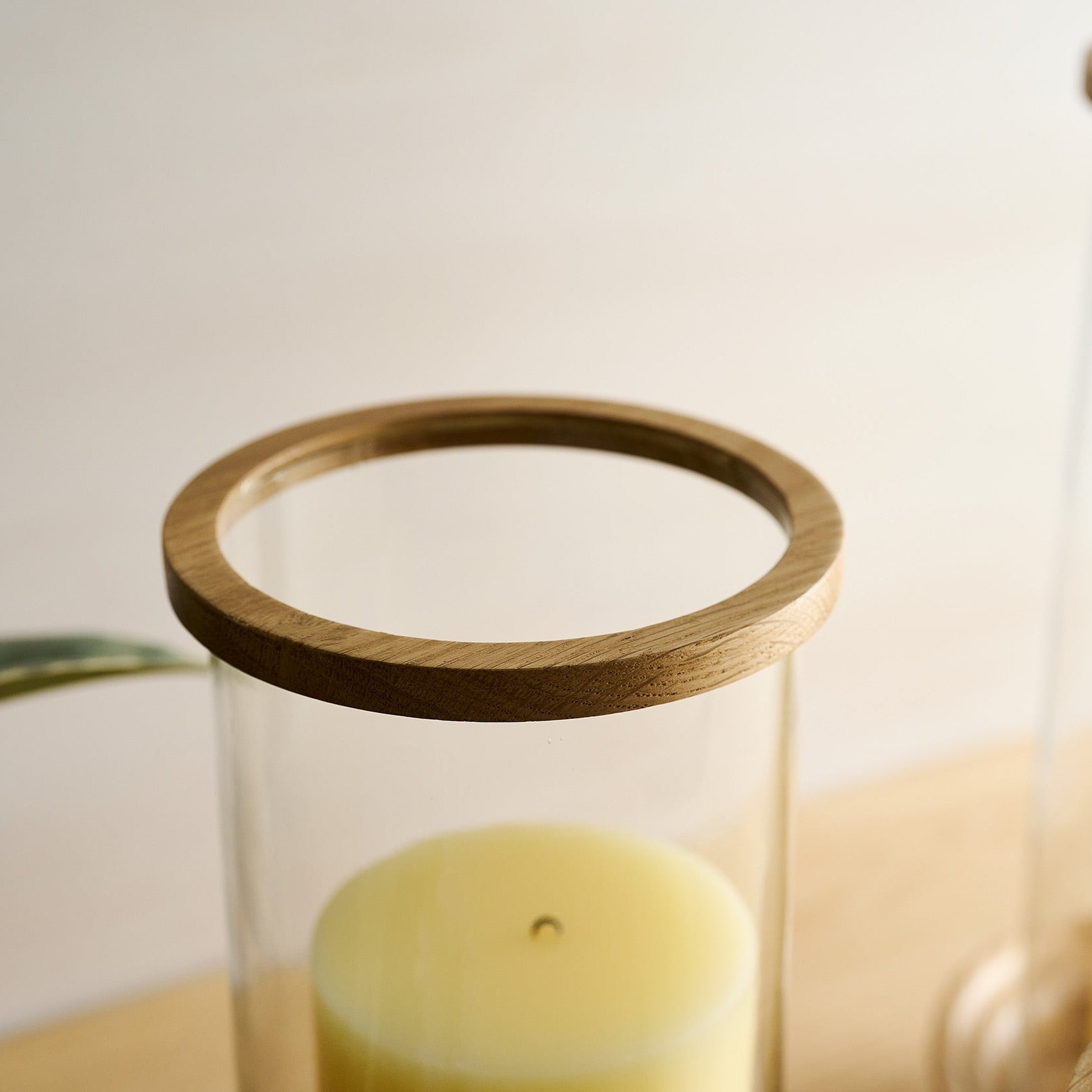 Glass candle holder with wooden top on a light background