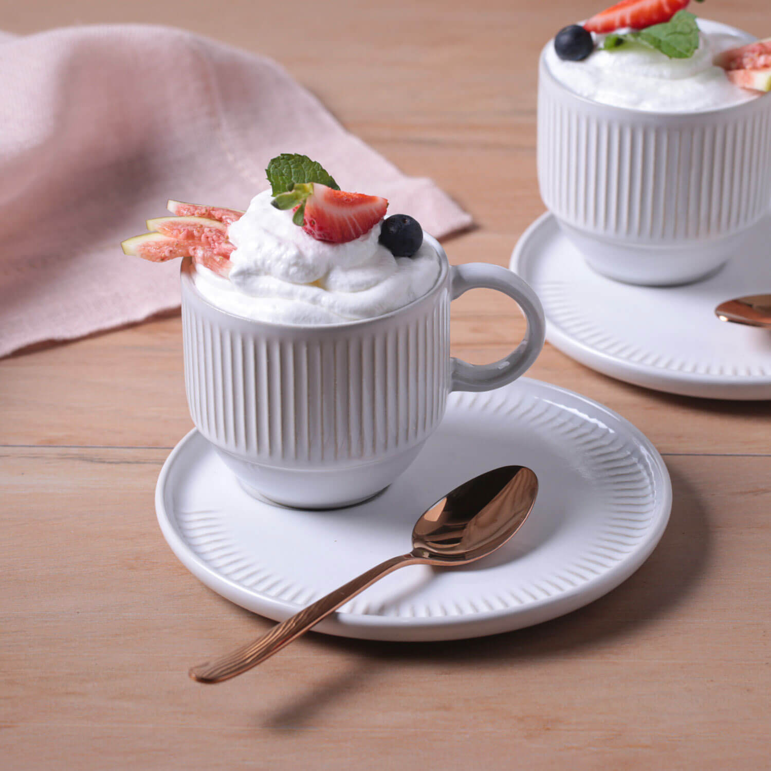 Two white ceramic mugs with dessert on a wooden table