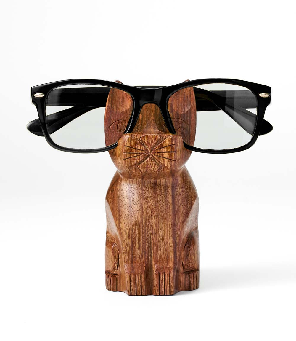 A handcarved sheesham wood eyeglass holder stand in the shape of a cat with eyeglasses placed on it