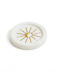 A round white marble incense holder with a gold radiating moon design in the center.