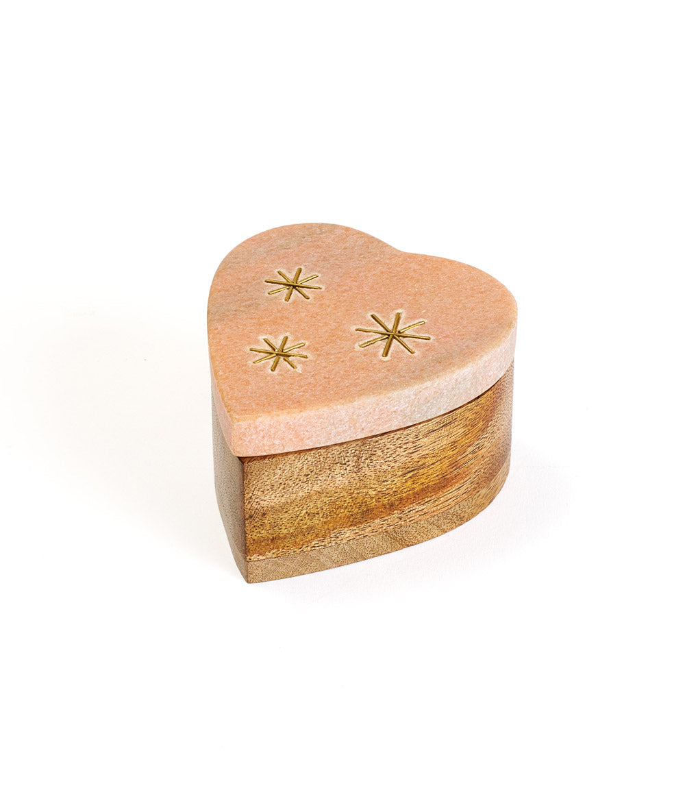 A heart-shaped pink marble keepsake box with brass stars inlay on the lid, set on a wooden base.