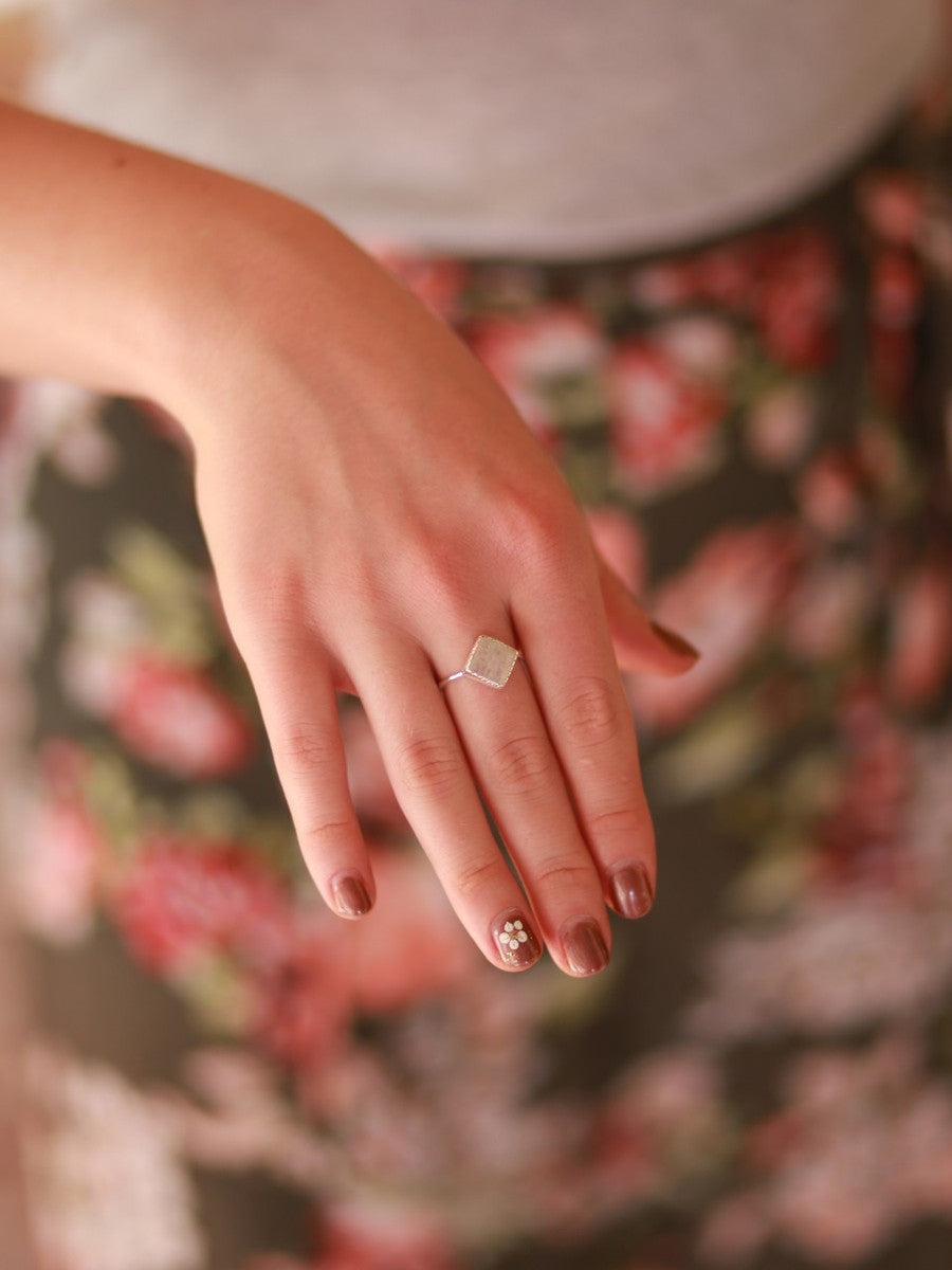 A hand wearing a ring made from .925 sterling silver and semi-precious moonstone.
