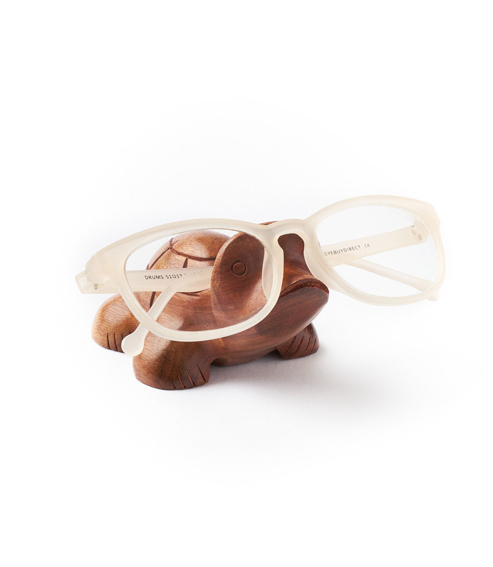 A rosewood turtle-shaped eyeglasses holder with a pair of eyeglasses resting on top of it