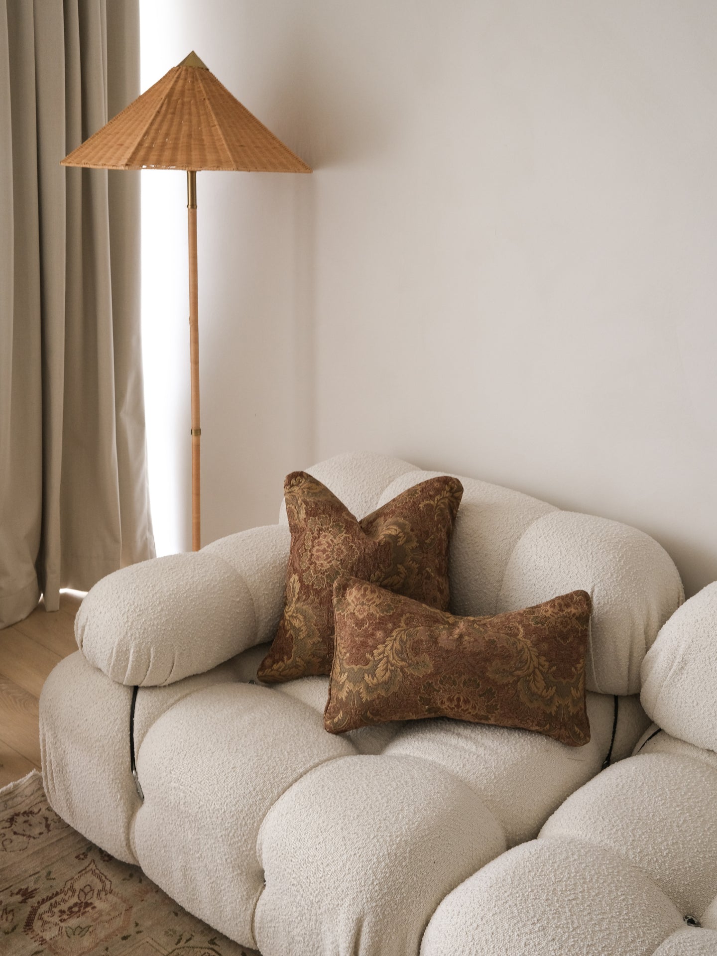 Beige sofa with brown textured pillows in a room with a standing lamp and curtains