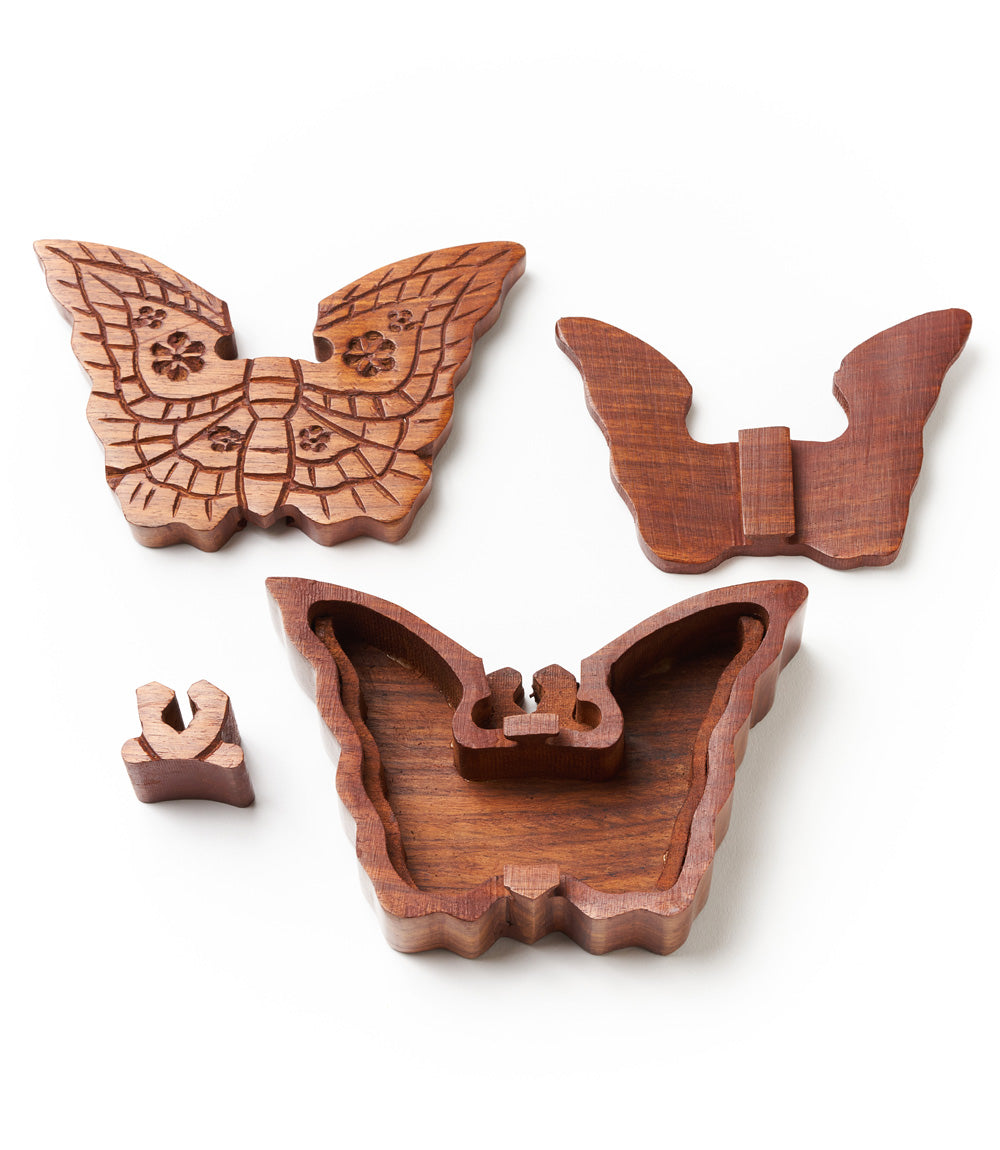 Pieces of a handcrafted wooden butterfly puzzle box made from solid Indian rosewood with intricate details resembling lace patterns.