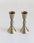 A pair of hand-forged iron candle holders with a brass finish, featuring a textured design.