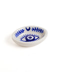 A hand painted blue and white ceramic incense holder with a geometric pattern and an evil eye motif in the center