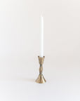 Bronze candle holder with a white candle on a light beige background