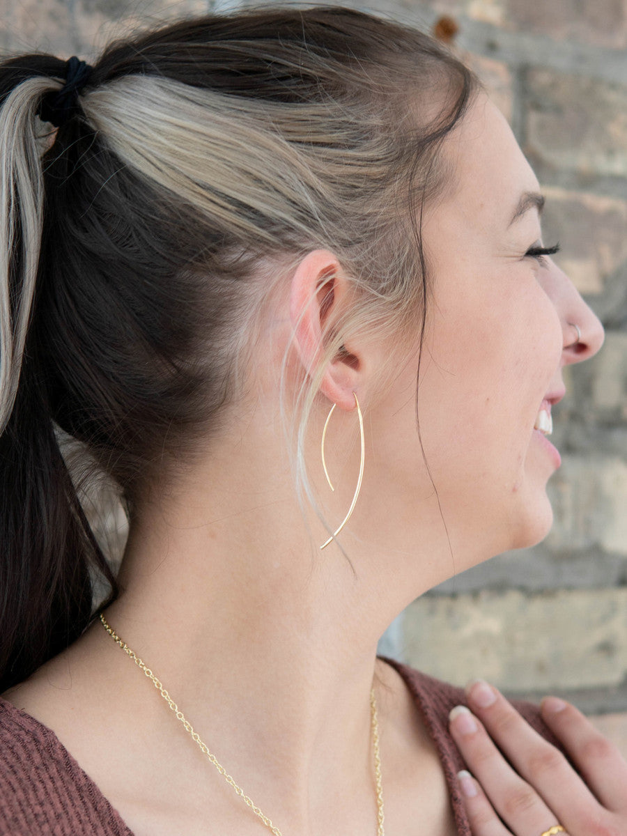 A model wearing a pair of brass recycled metal earrings.