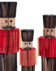 Recycled paper nutcrackers with red jackets and black hats on a white background