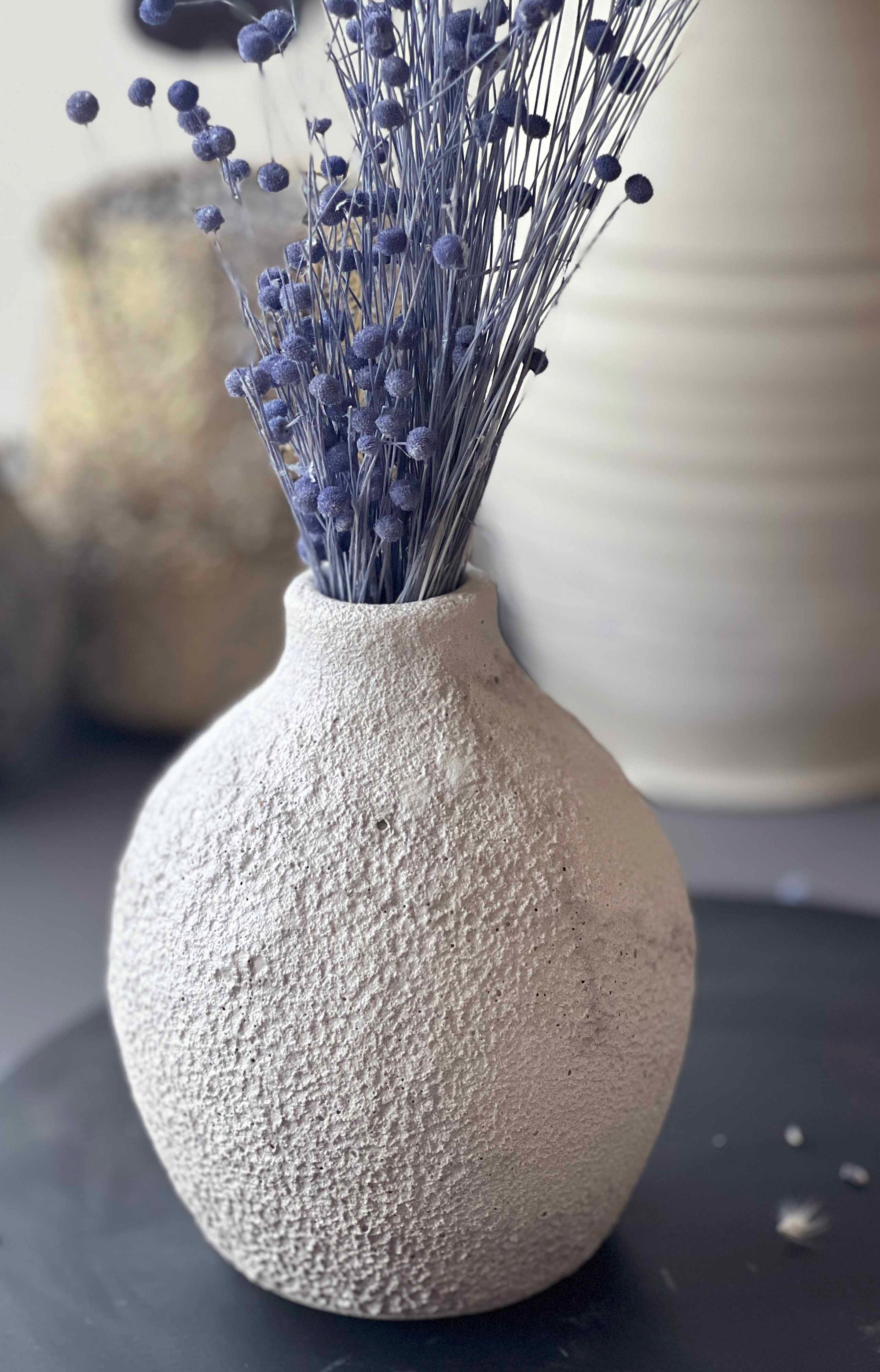 Textured vase with dried lavender on a dark surface