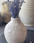 Textured vase with dried lavender on a dark surface