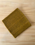 Folded green fabric square trivet on a wooden surface