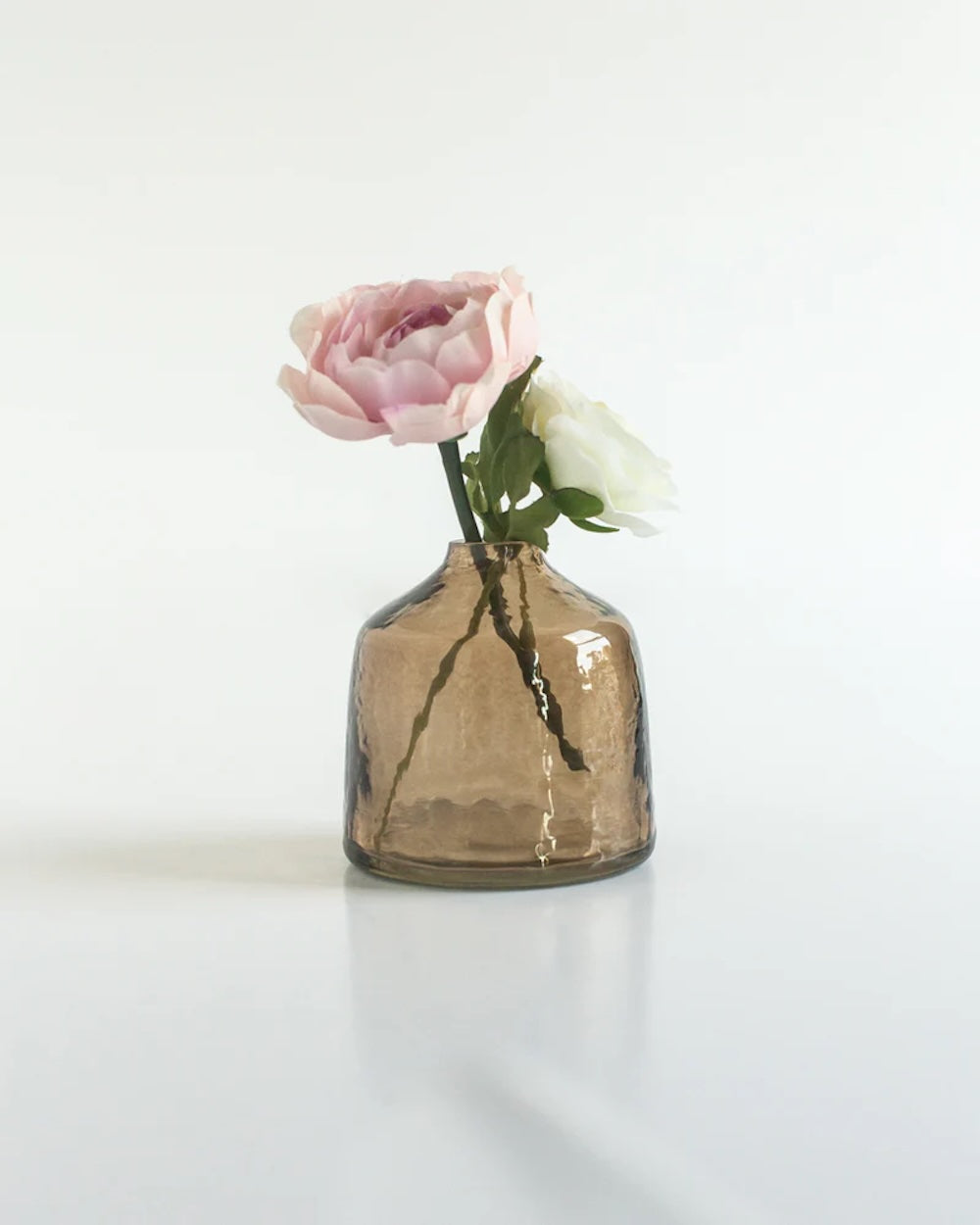 Smoked glass vase with a pink flower on a white background
