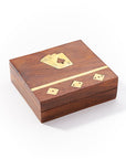 A wooden game night box with brass inlay, containing playing cards and dice, closed and placed on a white background.