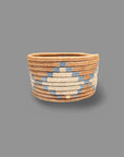 A handwoven trinket basket with blue and tan colors, circular base, and tightly coiled pattern