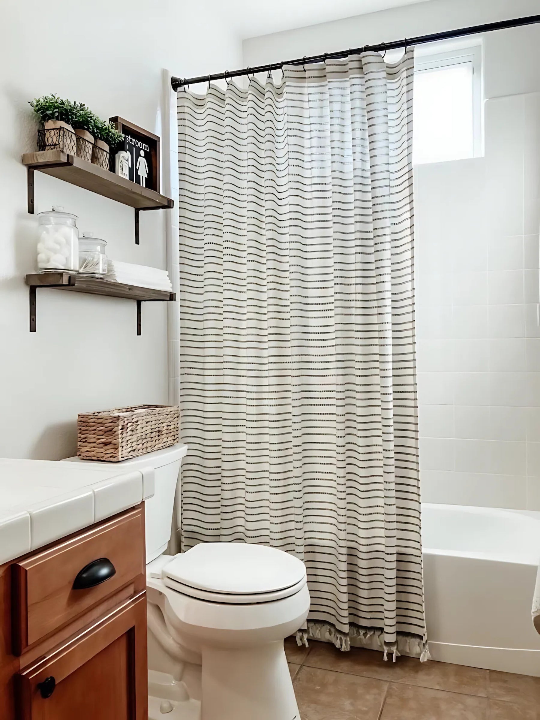 Bathroom with striped shower curtain, wooden shelves, and white fixtures