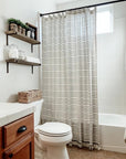 Bathroom with striped shower curtain, wooden shelves, and white fixtures
