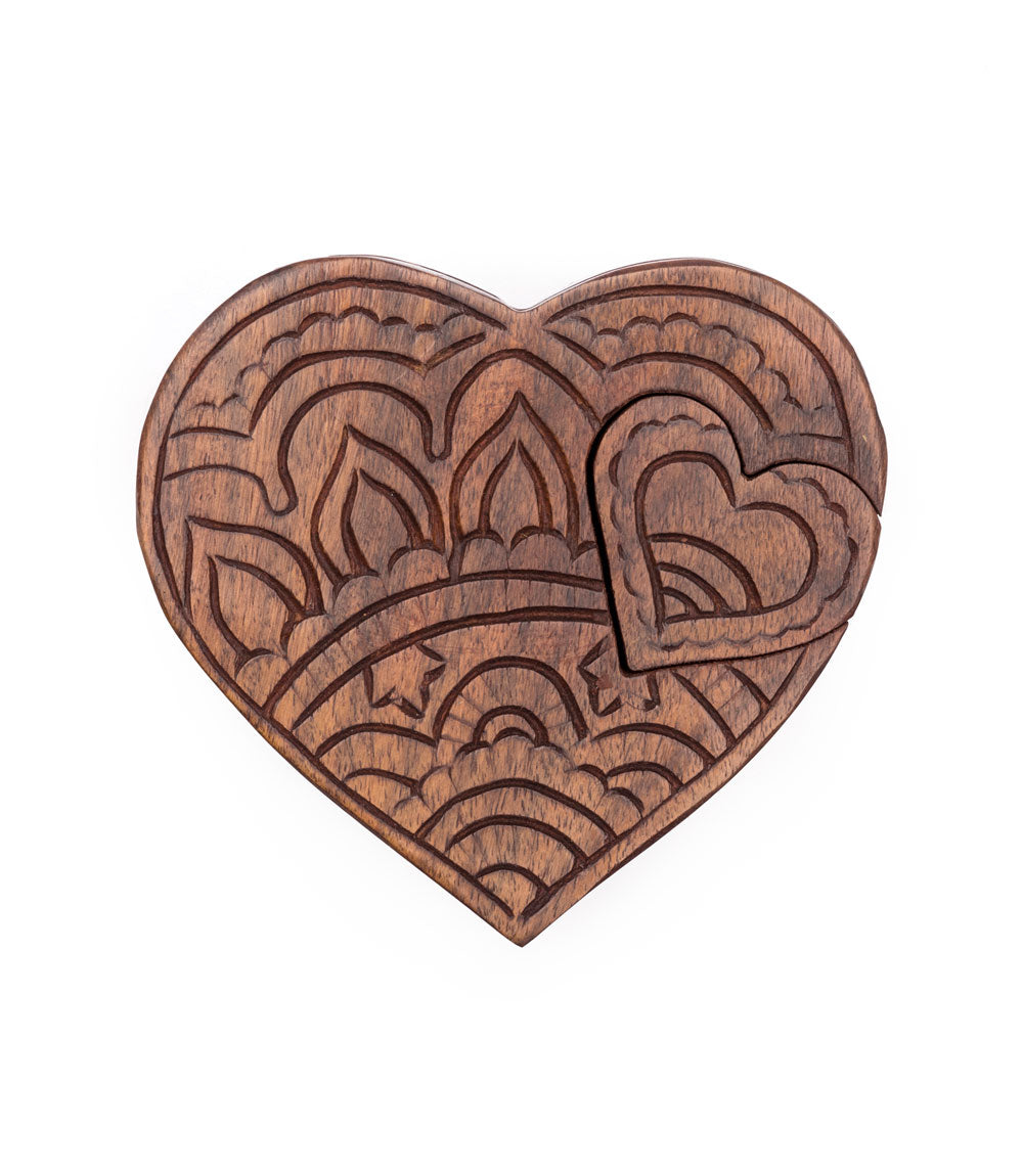 A hand-carved wooden puzzle box in the shape of a heart with intricate floral patterns.