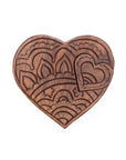A hand-carved wooden puzzle box in the shape of a heart with intricate floral patterns.
