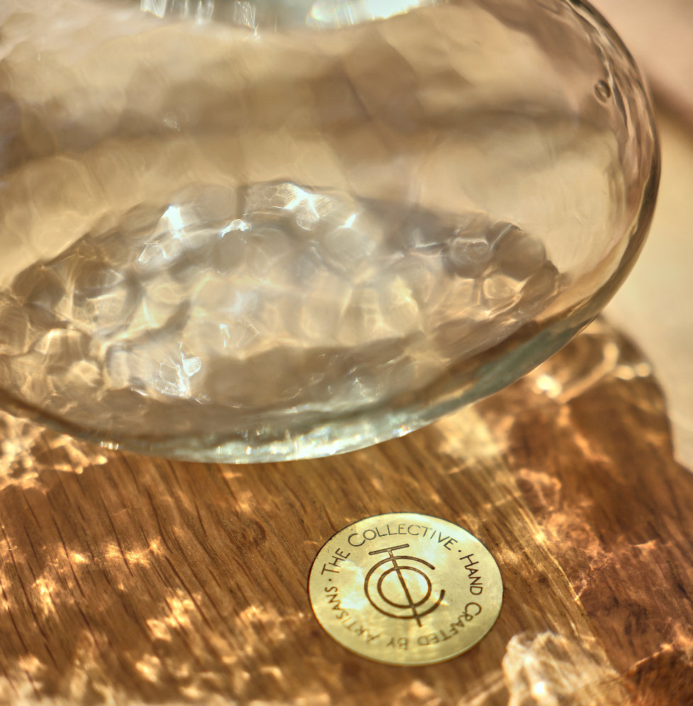 Glass bowl with a textured surface on a wooden surface, featuring a gold coin with text and symbols.