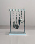 Metallic kitchen utensil set on a stand with a neutral background