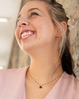 A model wearing a dainty black beaded gold necklace with a gold-plated chain and a larger black bead as the central piece