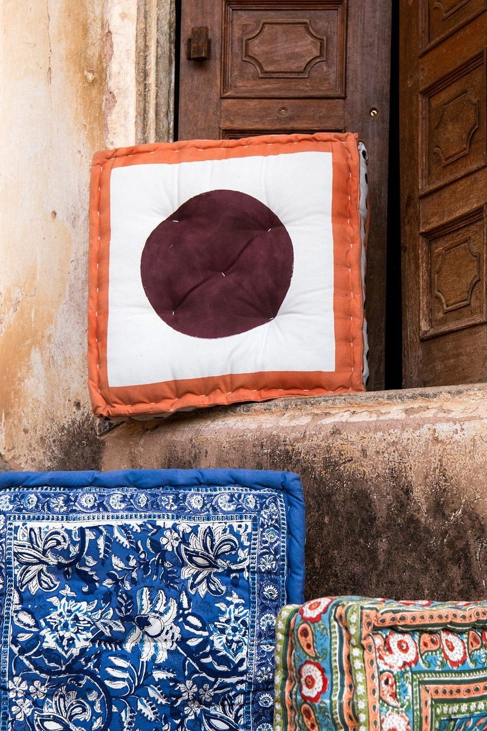 Decorative cushions with different patterns on a textured wall.