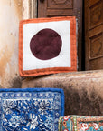Decorative cushions with different patterns on a textured wall.