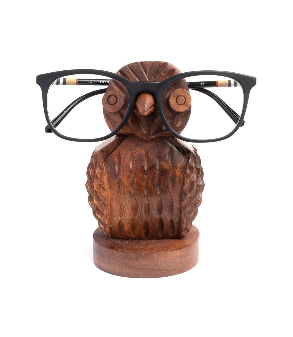 A hand-carved wooden owl eyeglass holder stand with a pair of glasses placed on it.