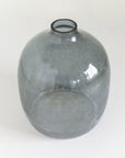 A blue grey hammered glass vase with a round shape on a white background.