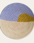 A handwoven basket with a geometric pattern in shades of blue, beige, and green, with a loop on the back for hanging