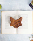 Hand-carved wooden fox face puzzle box with multiple pull-apart pieces on top of a book.