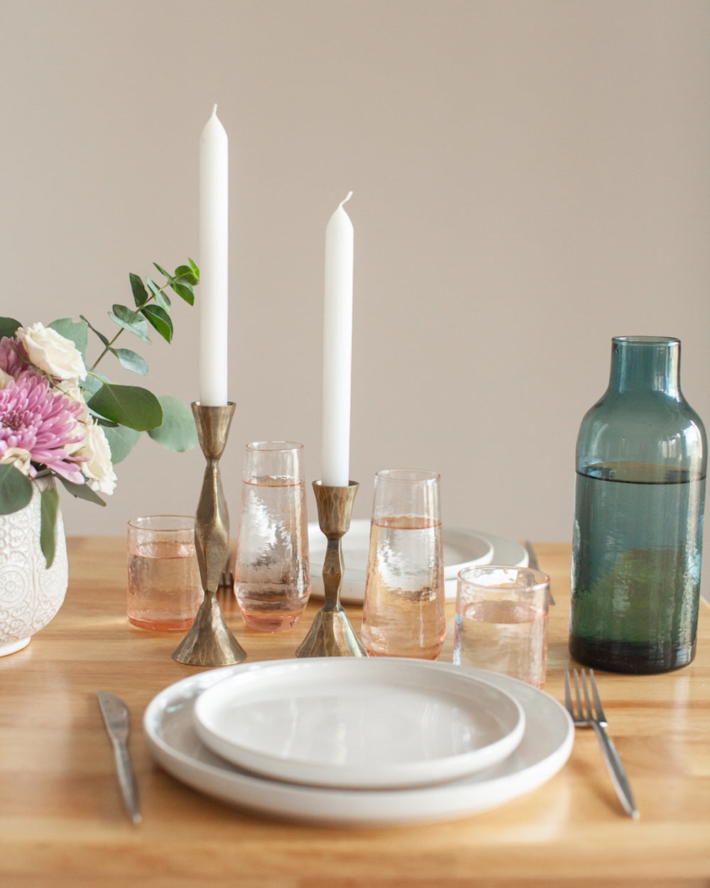 Elegant table setting with candles, flowers, and glasses.