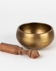 Bronze singing bowl with wooden striker on a white background