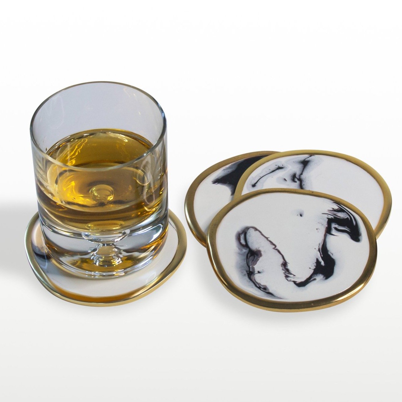 Glass of whiskey on a coaster with marble-patterned coasters around it