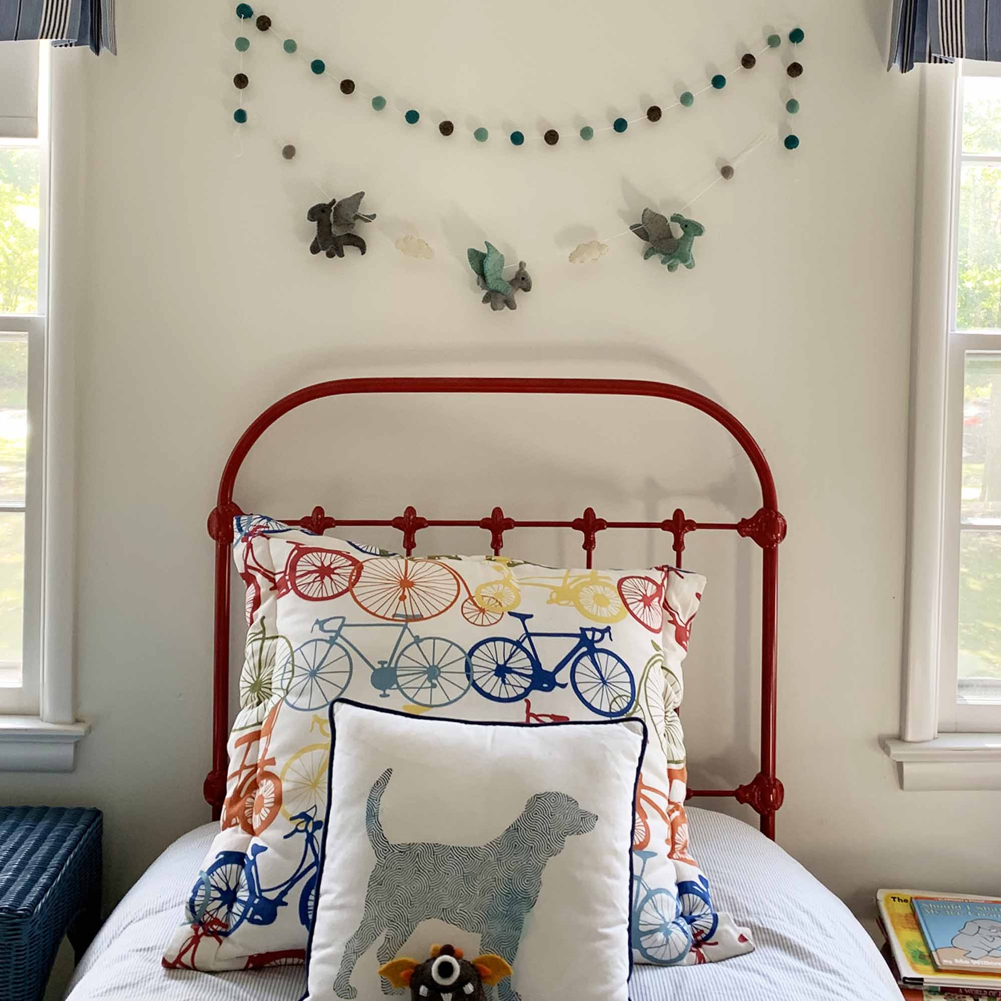 A handmade felt garland featuring multicolored dragon shapes hanging in a child's bedroom